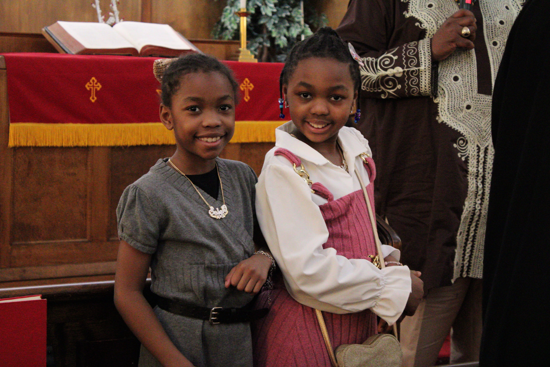 Two young girls smiling together in front of the altar during a church service