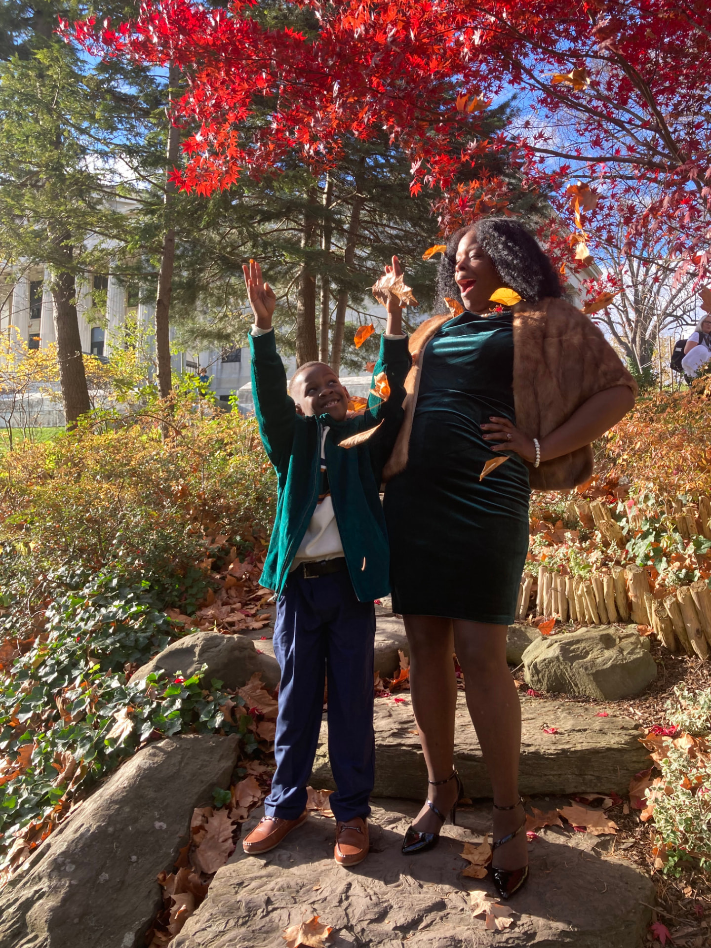 Mother and son tossing autumn leaves under a red maple tree in upstate New York