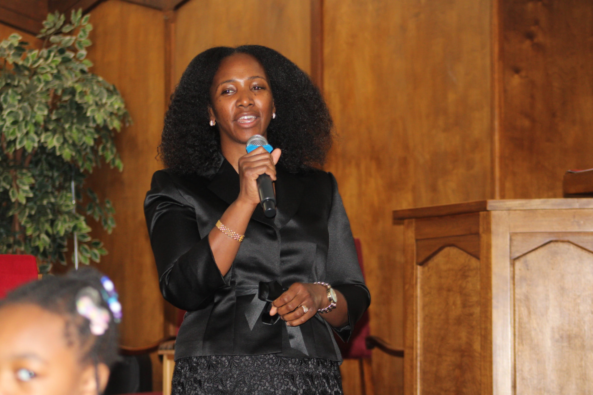 Woman speaking into a microphone beside the pulpit during a church service